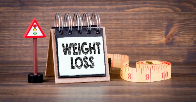 A note saying weight loss with an inch tape near it