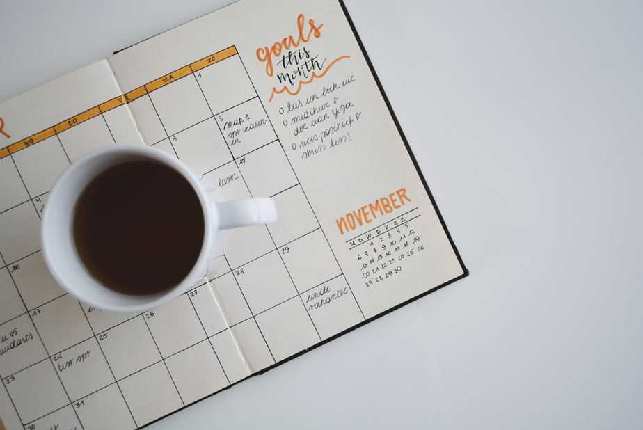 white ceramic mug with a liquid in it on top of a planner