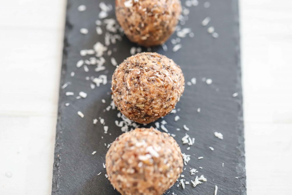 Protein balls on a slate surrounded by coconut shavings