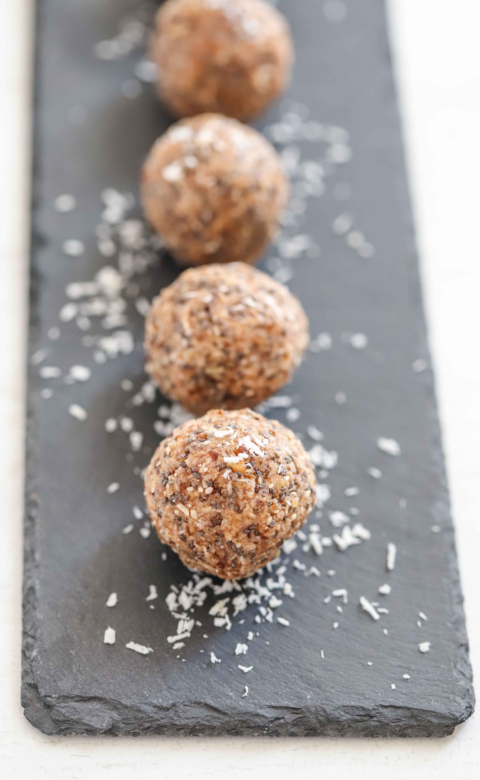 Protein balls on a serving slate with coconut shavings 