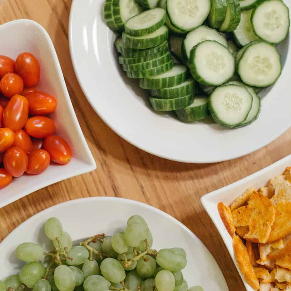 Green grapes, Cucumbers, and tomatoes on white plates