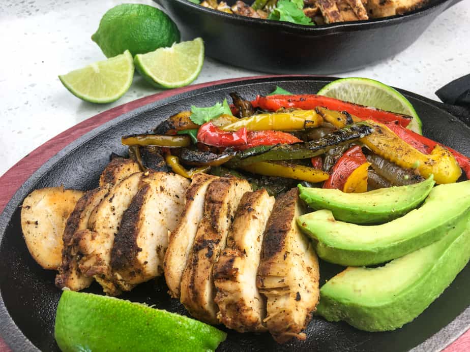 a skillet with chicken, avocado, limes and sautéd peppers