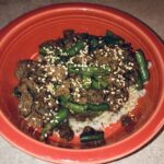 beef and green beans over brown rice, in an orange bowl