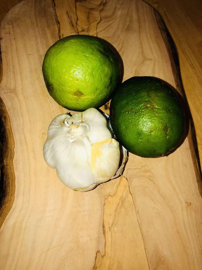 limes and a garlic bulb on a wooden cutting board