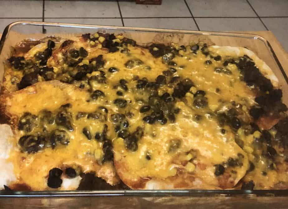 A glass dish with a layer of tortillas covered in cheese and black beans