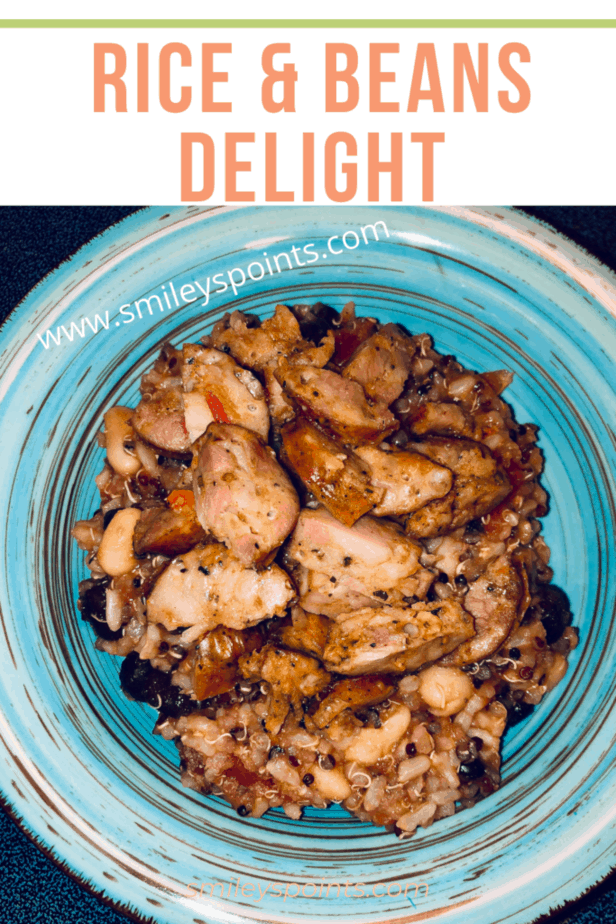 A teal bowl with rice, black beans, white beans and tomatoes with cut up sausage on top.