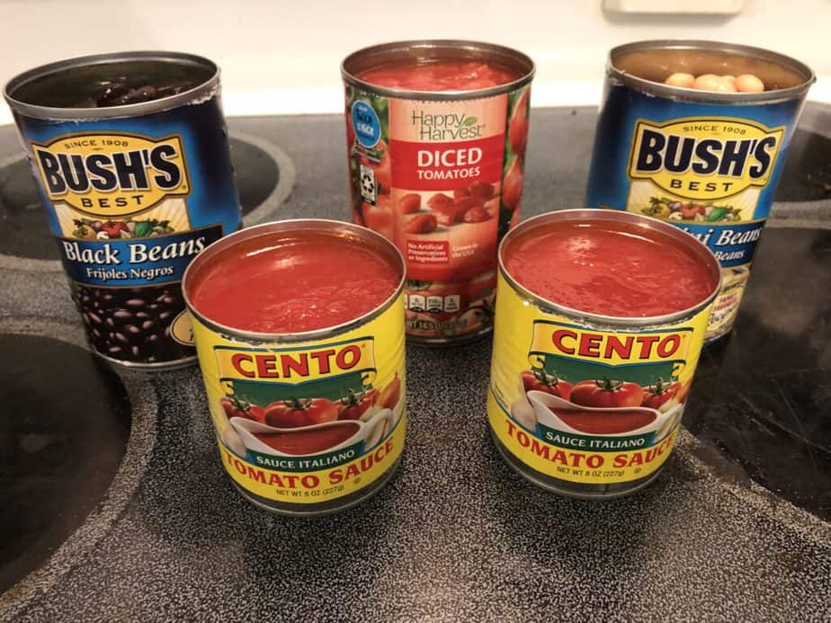 Open can of black beans, open can of cannellini beans, open can of diced tomatoes, two open cans of tomato sauce