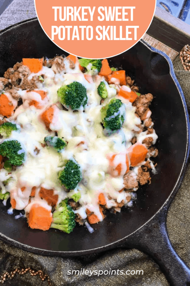 turkey sausage with sweet potatoes and broccoli in a cast iron skillet with melted mozzarella cheese