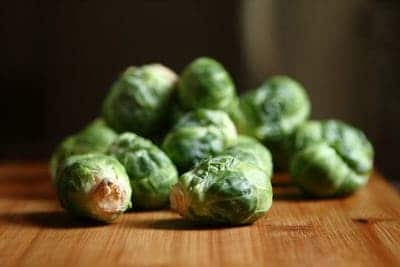 Brussels sprouts in a pile, on a wooden surface.