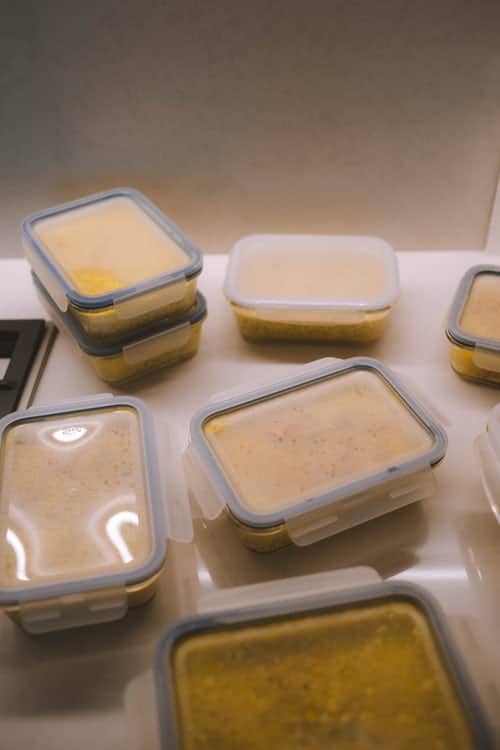 8 glass containers with something yellow in them and plastic lids