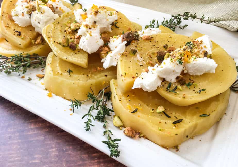 Golden Beets arranged on a white platter garnished with thyme and pistachios
