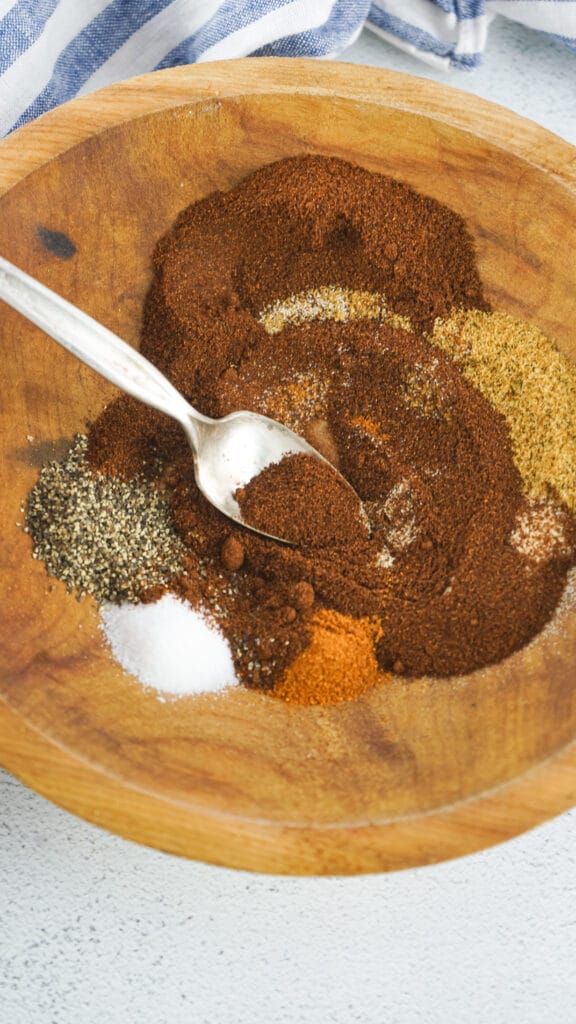chili seasonings in a wooden bowl beginning to be mixed up