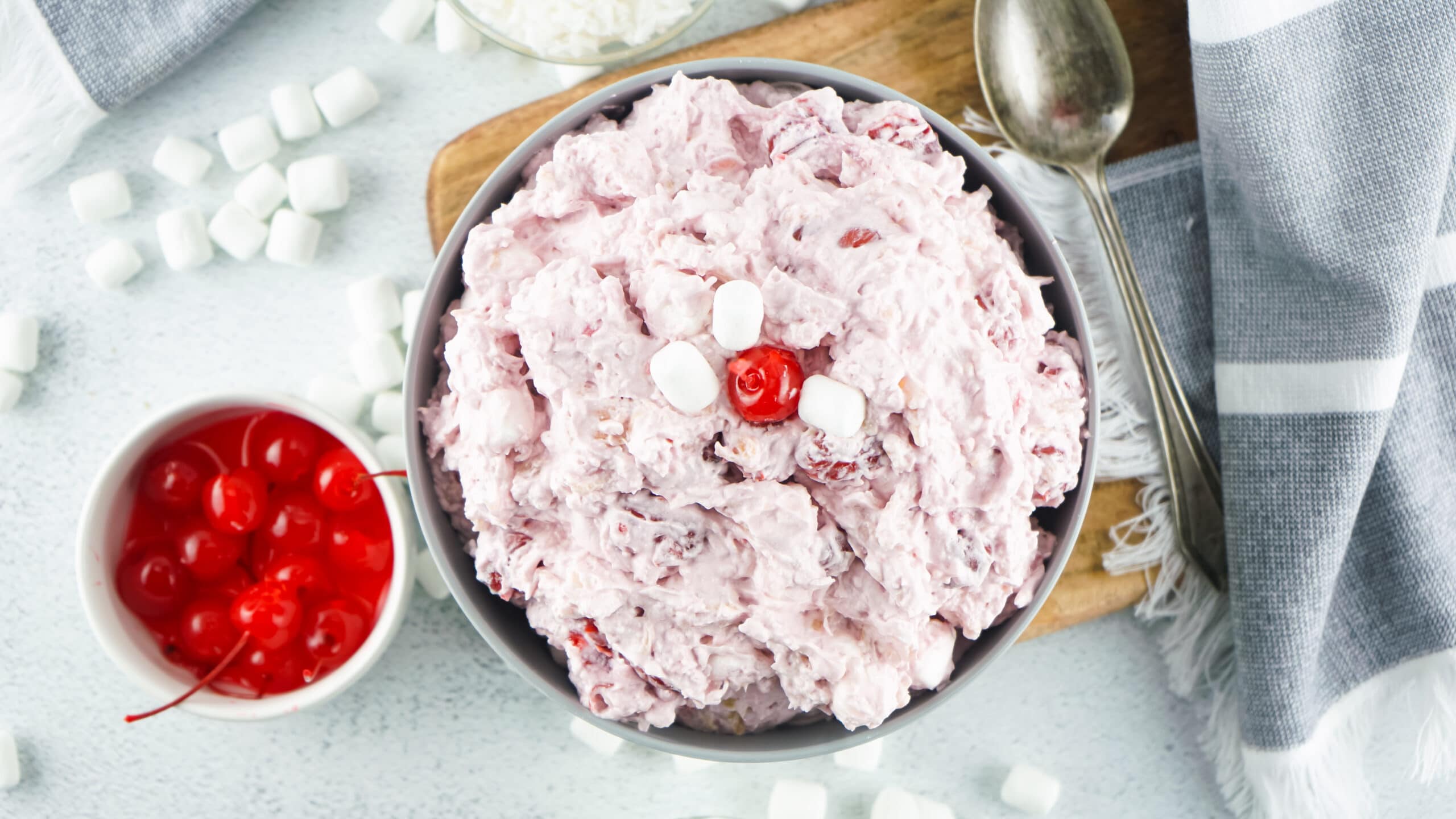 cherry fluff in a grey bowl with a bowl of cherries on the left side of it. top down view