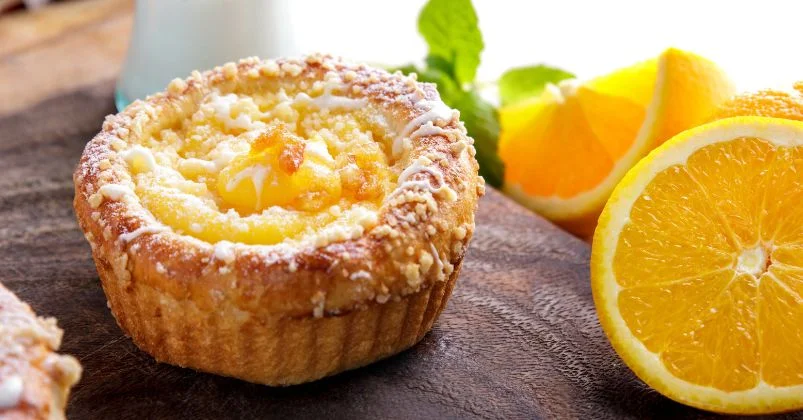 orange breakfast muffins ina muffin pan on a white table