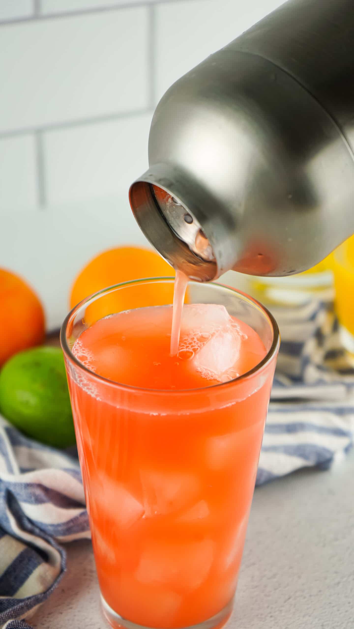 a drink in a glass being poured form a silver shaker