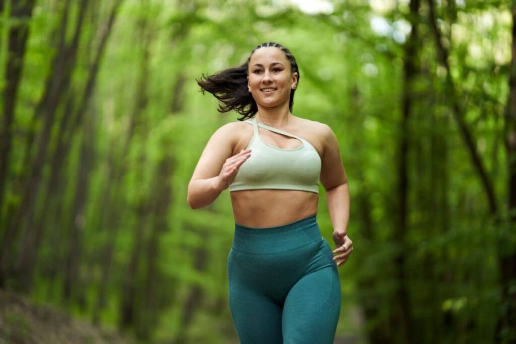 Woman smiling while running through forest
