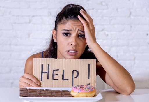 Young worried latin woman feeling tempted and guilty wanting to eat chocolate and donuts asking for help in diet calories sugar addiction nutrition and lifestyle concept.