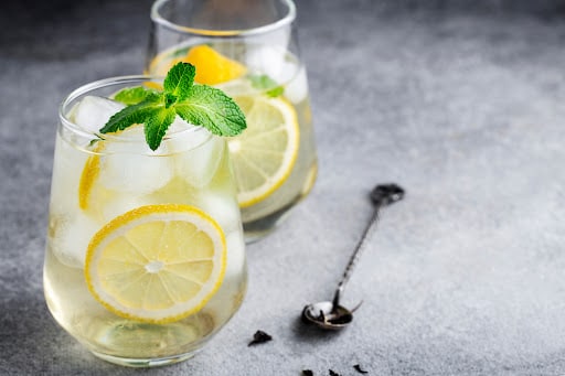 cold sparkling green tea with lemon, mint and ice, glasses on a grey background, summer drinks, lemonade