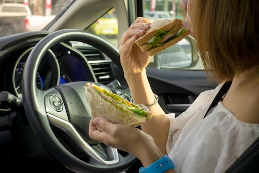 Woman eating healthy sandwich while sitting in her car.