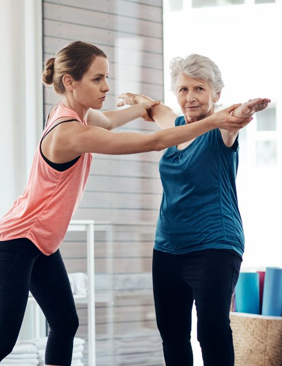 a senior woman engaged in fitness exercises under the guidance of her personal trainer.
