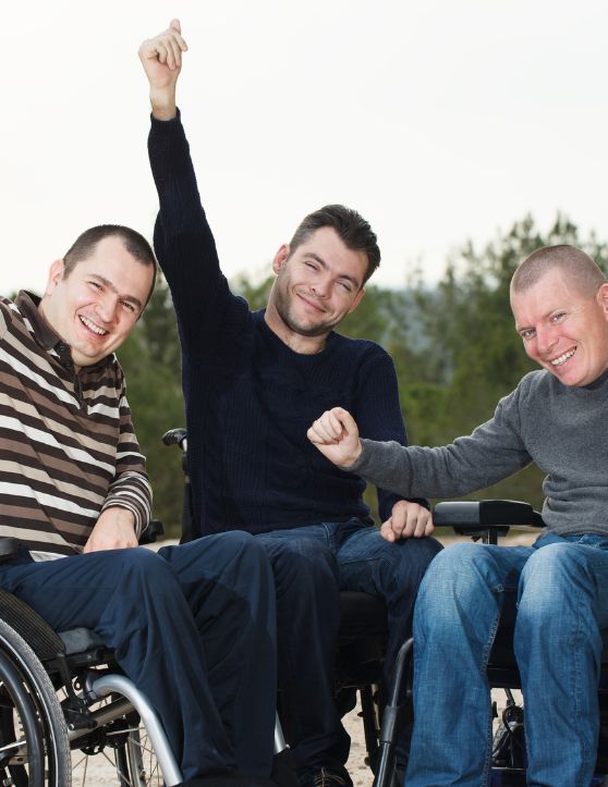 Three individuals in wheelchairs express jubilation and cheerfulness as they celebrate the completion of their exercises