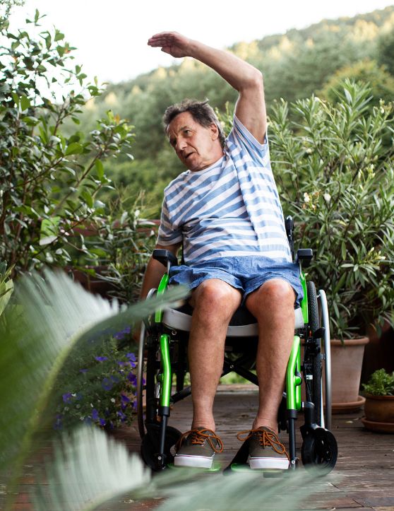 Elderly man in a wheelchair doing exercises in the garden.