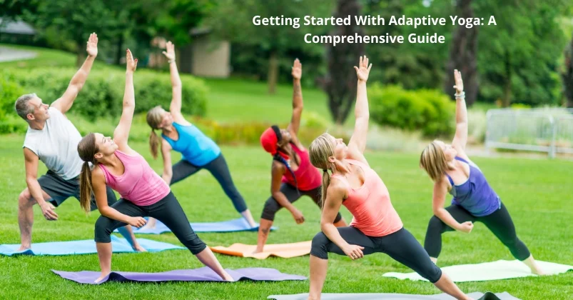 image shows a group of people practicing yoga outdoors on mats. The participants are engaged in a side stretch pose, and the setting is a lush green park