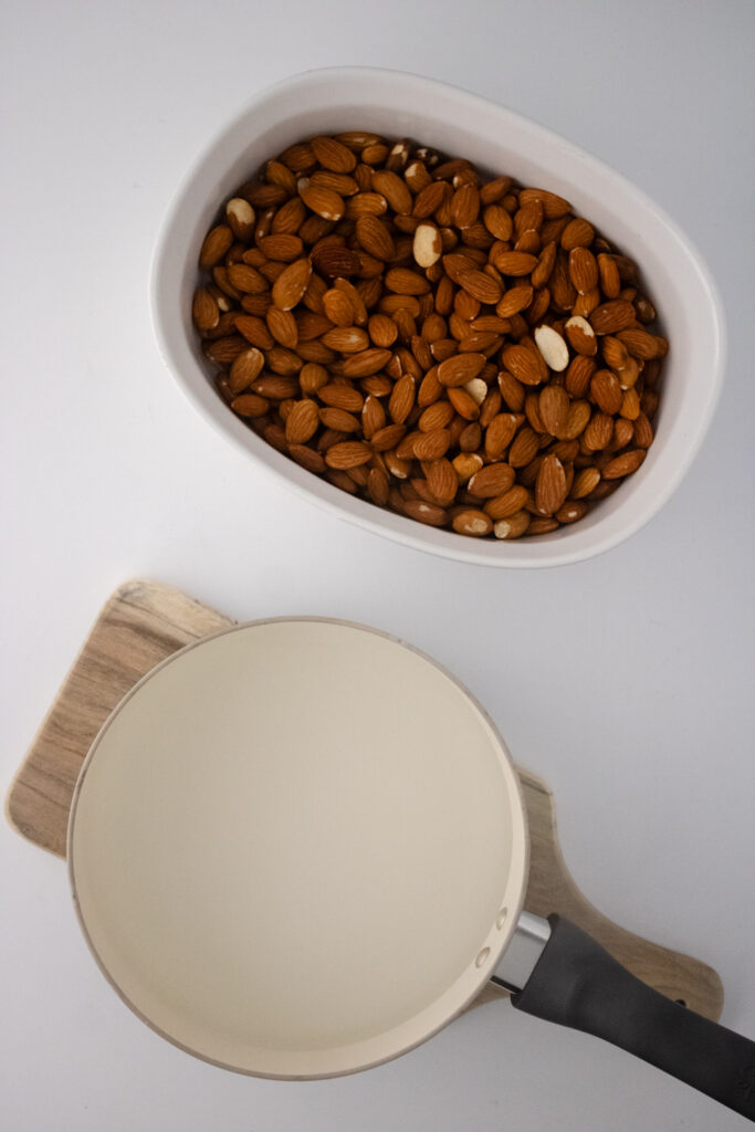 Raw Almonds In a White Bowl Along With A Pot Of Hot Water