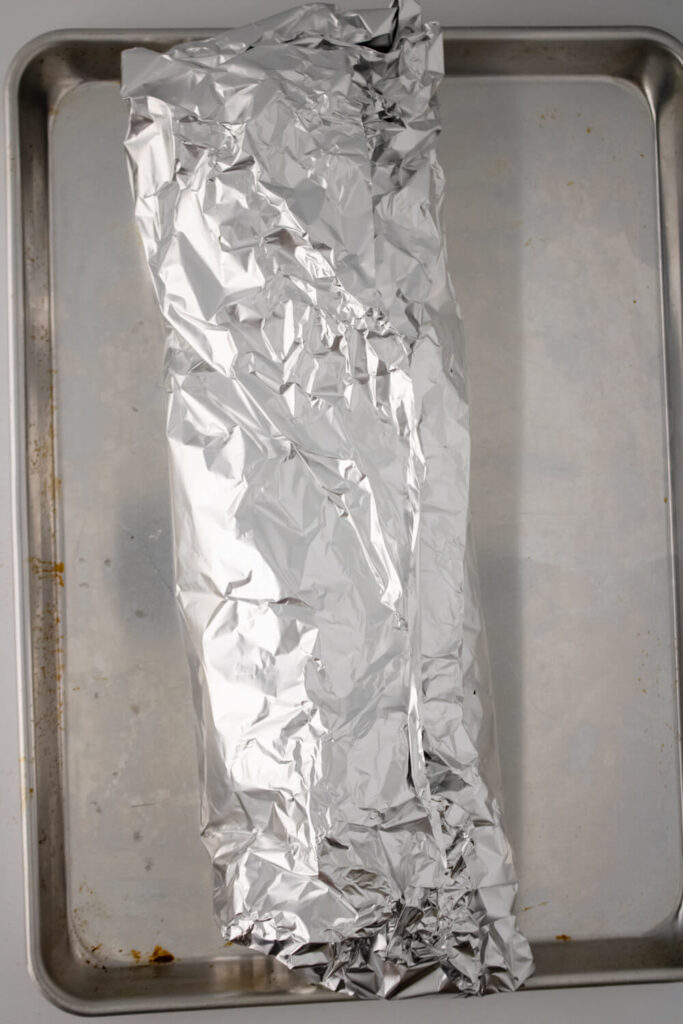 wraped baby back rib in foil placed on baking sheet