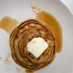 banana oat pancake with honey and butter placed on white plate