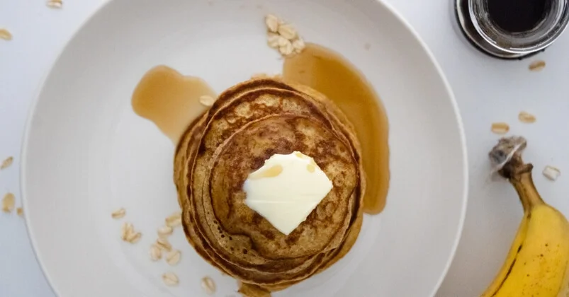banana oat pancake with honey and butter placed on white plate