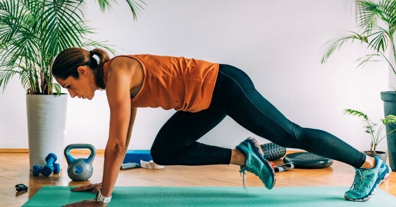 a woman in workout gear doing a mountain climber exercise on a yoga mat indoors