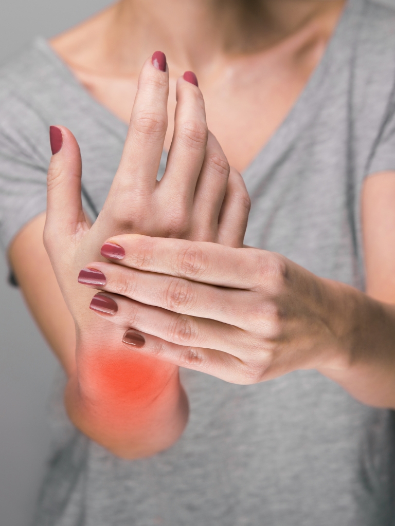 close-up of a person holding their wrist, which is highlighted in red, indicating pain in the area