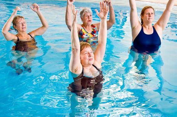 image shows a group of elderly women participating in an aqua fitness class in a swimming pool